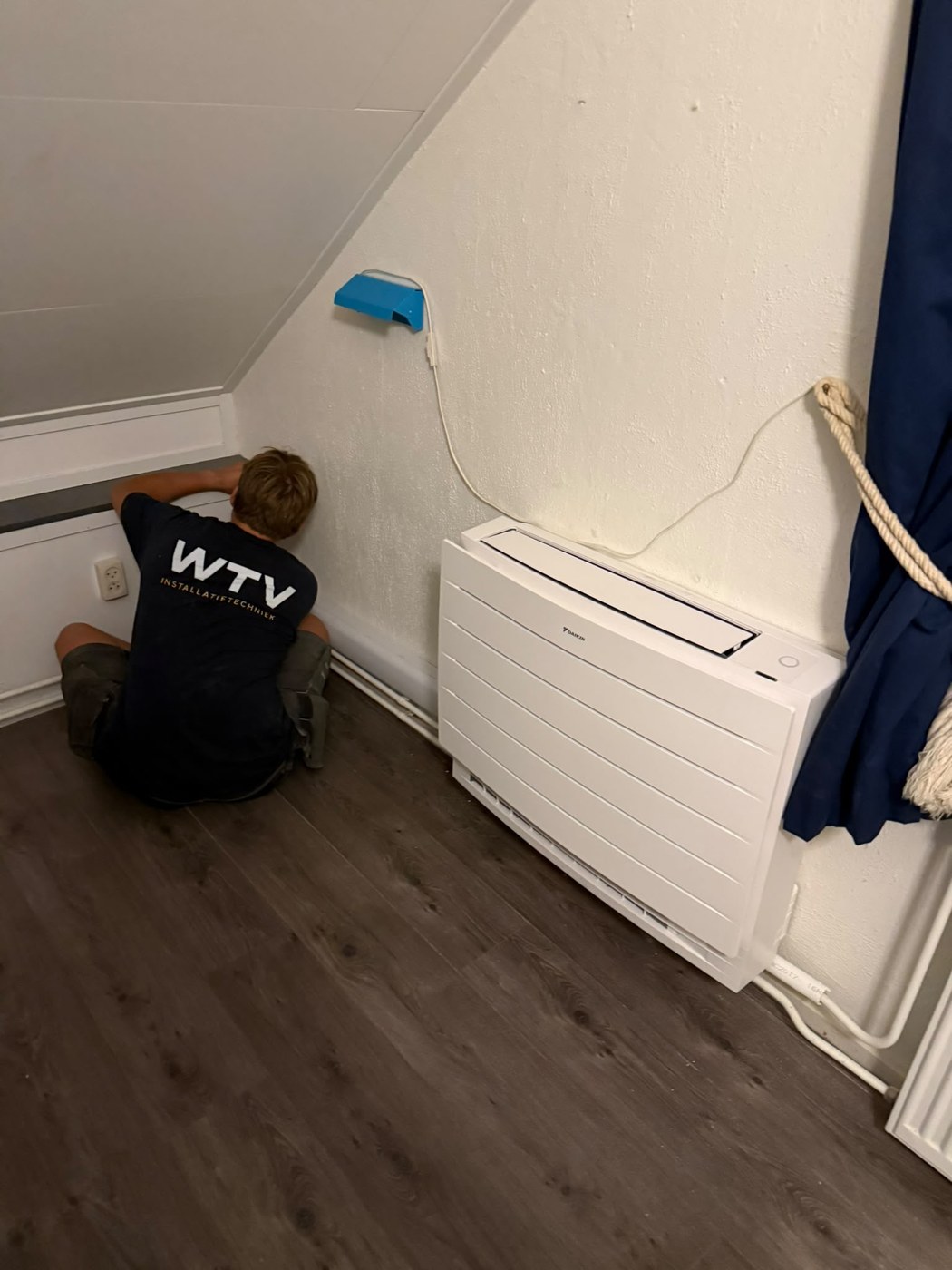 WTV-monteur installeert een airco-vloermodel in een woning